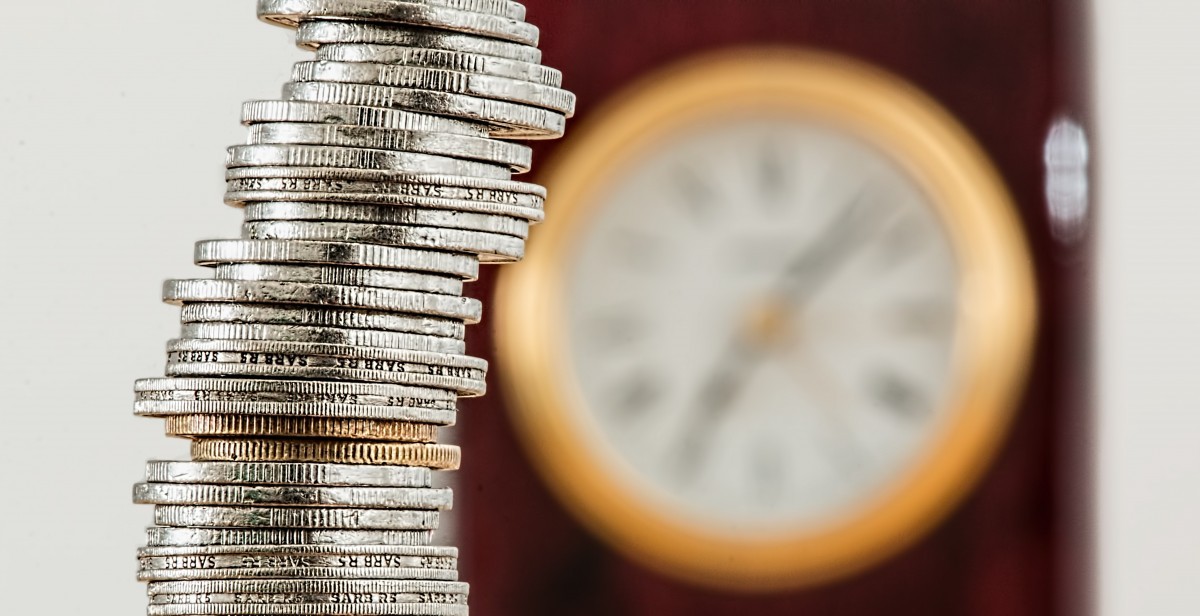 a stack of coins beside a blurry clock